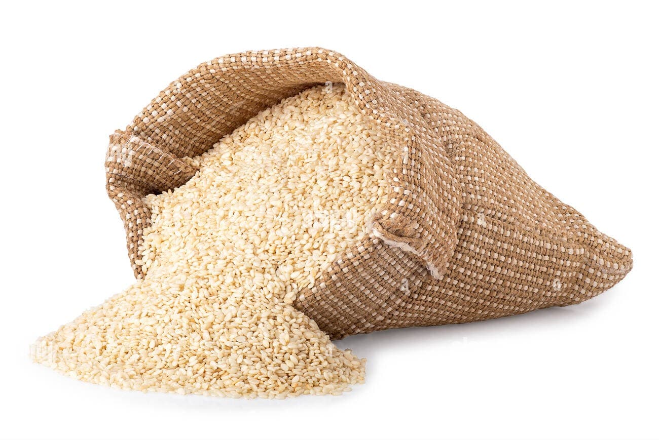 Bag of sesame seeds spilling onto a white surface